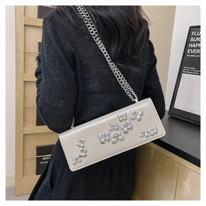 Detailed view of beige crossbody bag with silver butterflies and chunky chain strap