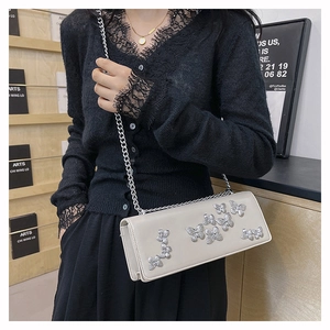 Close-up of cream butterfly crossbody bag with silver butterfly charms and metal chain