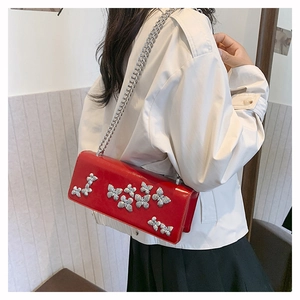 Close-up of red leather butterfly crossbody bag with silver chain on model