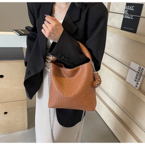 Detail der braunen Web-Eimertasche mit silberner Kette und Herz-Anhänger