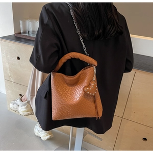 Braune Beuteltasche mit Krokoprägung, Silberkette und Herzanhänger an einem Modell
