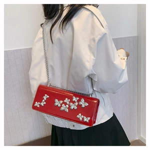 Detail of red butterfly crossbody bag with silver chain worn over a white and black outfit