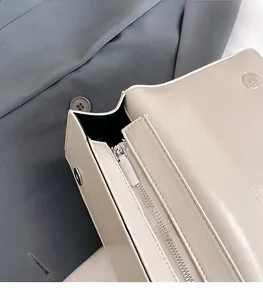 Close-up of silver metal hardware zipper and magnetic snap on a beige leather bag