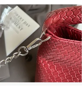 Detaillierte Makroaufnahme von silbernen Metallhaken und Ketten an einer roten Web-Handtasche