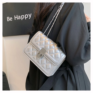 Detail of silver metallic quilted crossbody bag with chain strap on a model