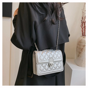 Detail of silver quilted chain bag featuring a metallic finish and rectangular turn-lock