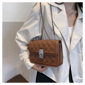 Close-up of brown quilted leather bag with silver chain strap and metal turn-lock