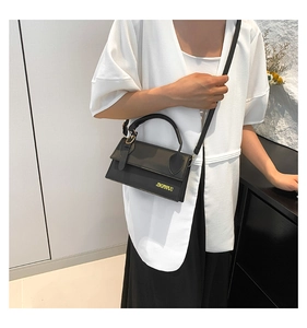 Détail du sac à bandoulière noir avec texture mate et lettrage de marque doré