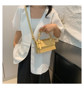Détail d'un sac bandoulière minimaliste en cuir jaune crème porté par un mannequin