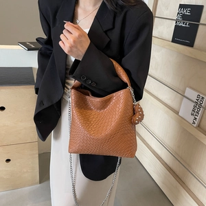 Braune geflochtene Eimertasche aus Leder mit Griff und Kettenriemen am Modell gezeigt
