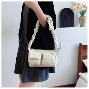 Detail of cream PU leather shoulder bag featuring pleated strap and multi-pocket design