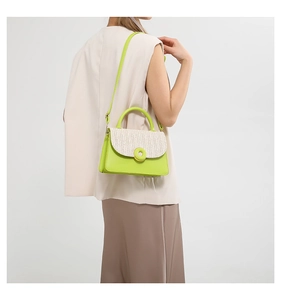 Detail of neon green crossbody bag featuring straw woven flap and round buckle