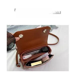 Detail view of brown leather bag interior with multiple compartments and makeup storage