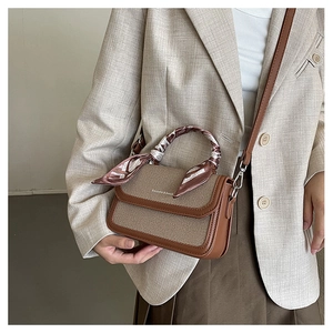 Detail of vintage canvas crossbody bag with silk scarf handle on a model in beige suit