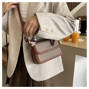 Detailed shot of textured canvas crossbody bag with elegant silk scarf wrapped handle