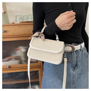 Detail of beige textured crossbody bag with floral silk scarf wrapped around the handle