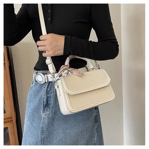 Detail showing cream woven texture bag with decorative scarf-wrapped handle and leather flap