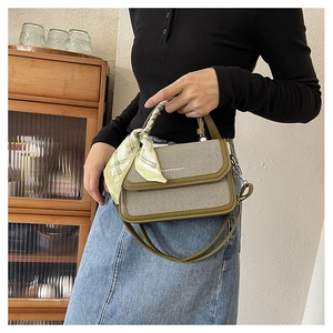 Detail of a beige and olive green crossbody bag with decorative scarf handle and strap