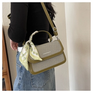 Detail of green leather and striped canvas handbag with silk scarf on handle