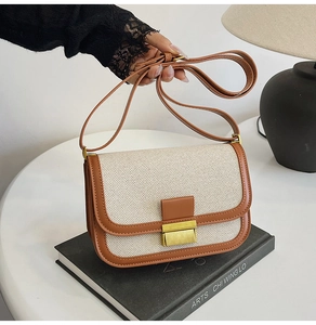 Detail of vintage linen and brown leather crossbody bag with gold buckle on a book