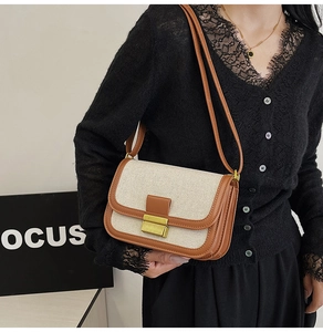 Detail of linen and brown leather crossbody bag with golden rectangular clasp