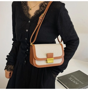 Detail of linen canvas crossbody bag featuring brown leather trim and golden metal lock