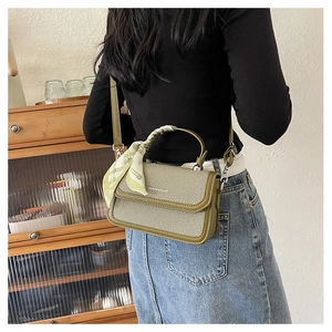 Olive green crossbody bag with textured surface and silk scarf wrapped handle detail