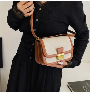 Detail of linen and brown leather crossbody bag with gold buckle and accordion layers