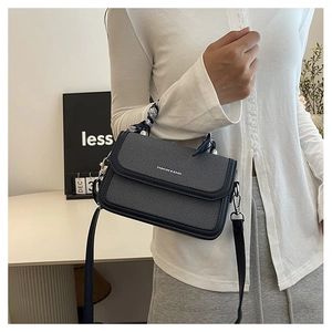Close-up of denim texture crossbody bag featuring a silk scarf wrapped handle and logo