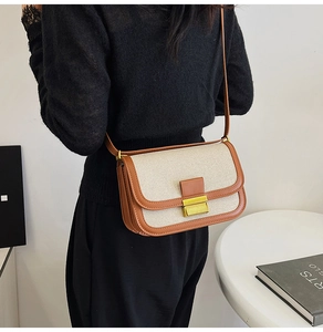Detail of vintage linen and brown leather crossbody bag with a gold buckle on model
