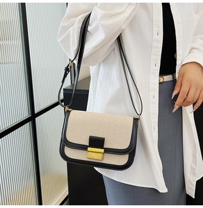 Detail of linen and leather patchwork crossbody bag featuring a gold square metal clasp