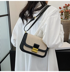 Chic beige linen and black leather crossbody bag with a gold clasp on a model