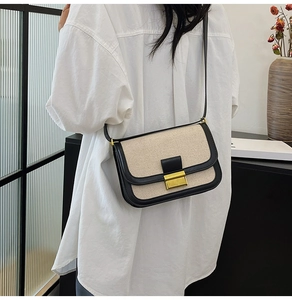 Detailed view of linen and black leather crossbody bag with a gold metallic buckle