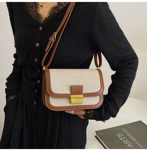 Detail of vintage linen crossbody bag with brown leather trim and golden metal clasp