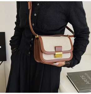 Detailed view of linen and brown leather patchwork bag with gold metal buckle