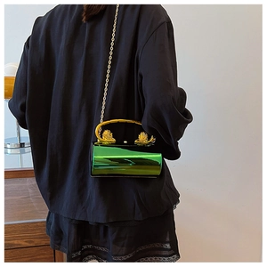Close-up of emerald green hard shell clutch bag with gold lion head handles and chain