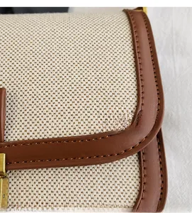 Detail of linen canvas and brown leather trim with fine stitching and gold metal buckle
