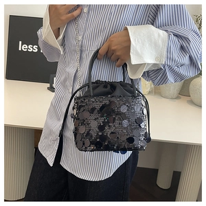Detail of black sequined bucket bag featuring drawstring closure and chain strap