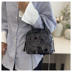 On-body view of black sequin bucket bag with silver chain strap and drawstring inner