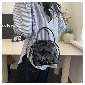 Close-up of black sequined bucket bag with drawstring closure and metal chain strap