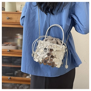 Gros plan d'un sac seau à paillettes argentées avec bandoulière chaîne et cordon gris