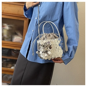 Close-up of a silver sequin bucket bag with drawstring interior and chain strap