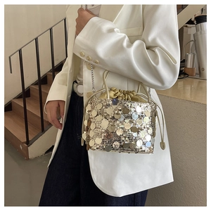 Close-up of golden sequins and drawstring closure on bucket bag with metal chain
