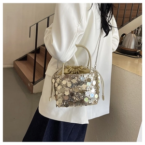 Detailed view of bucket bag with gold sequins, mustard drawstring pouch and chain strap