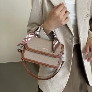 Minimalist beige woven handbag with brown leather trim and decorative silk scarf