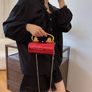 Red hard-shell cylindrical evening clutch bag with golden lion head handles and chain