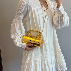 Golden cylindrical evening clutch with lion head handle and sleek metallic mirror finish