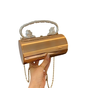 Golden cylindrical clutch bag with lion head handles and crossbody chain strap