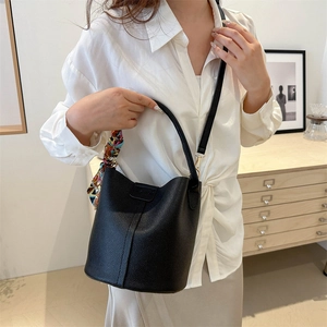 Fashion black lychee leather bucket bag with silk scarf handle on modern background