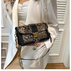 Close-up of vintage snakeskin crossbody bag featuring gold butterfly buckle and chain strap